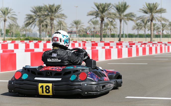 Go-kart racing at YAS Marina Circuit Kartzone with palm trees in the background.