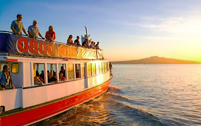 Auckland Harbour cruise boat at sunset with Rangitoto Island in the background.