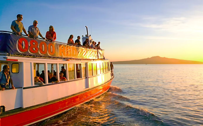Auckland Harbour cruise boat at sunset with Rangitoto Island in the background.