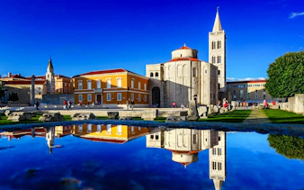 Historic Church of St. Donatus and Bell Tower in Zadar, Croatia, reflected in water.