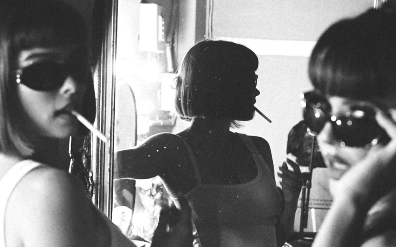 Person in sunglasses with a cigarette, reflected in a mirror, Brisbane nightlife.