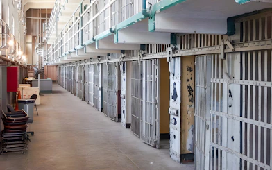 Prison cells on Alcatraz Island, San Francisco, with open barred doors and a walkway.