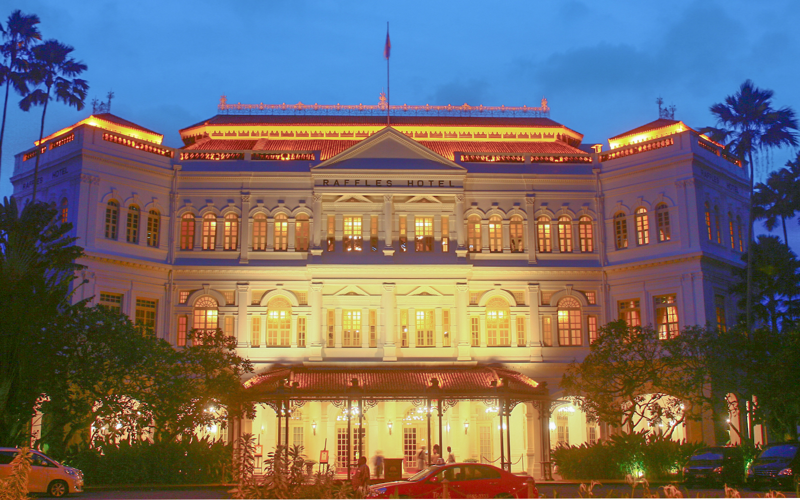 Raffles hotel illuminated with yellow lights in Singapore at night