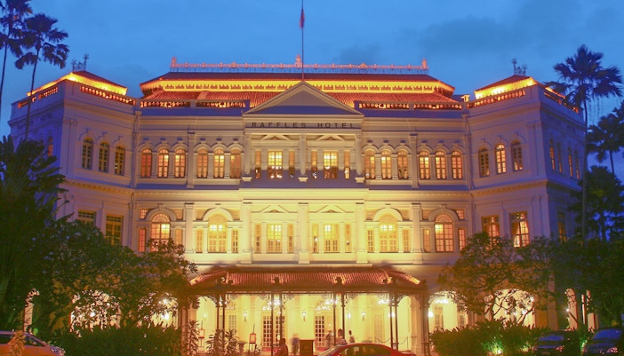 Raffles hotel illuminated with yellow lights in Singapore at night