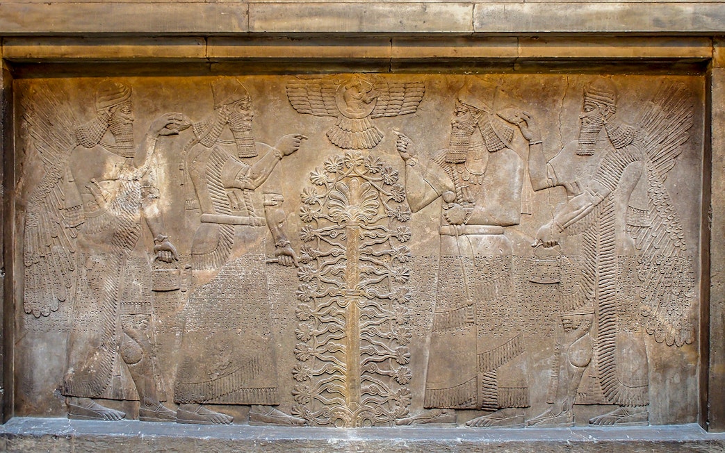 Ancient Assyrian relief depicting winged figures and sacred tree at British Museum.