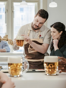 Tour guide explaining beer pouring technique at Pilsner Urquell brewery.