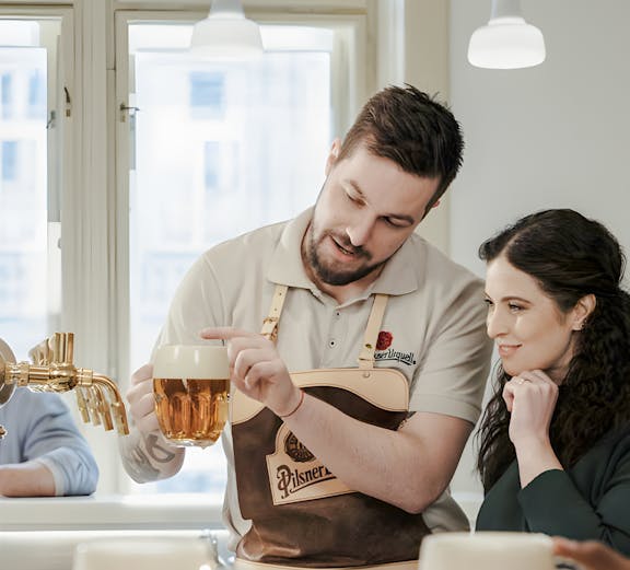 Tour guide explaining beer pouring technique at Pilsner Urquell brewery.