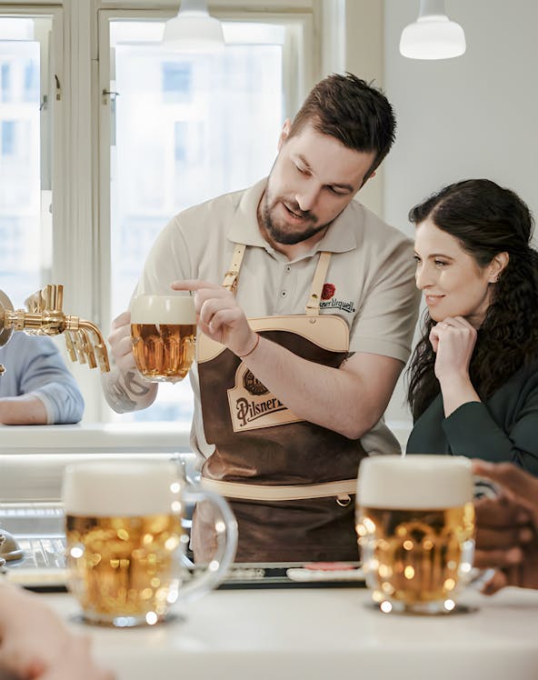 Tour guide explaining beer pouring technique at Pilsner Urquell brewery.