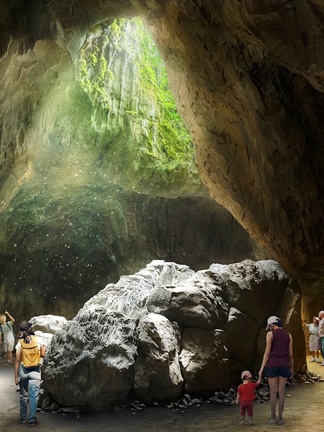 Visitors exploring a sunlit cave in Rainforest Wild Asia.
