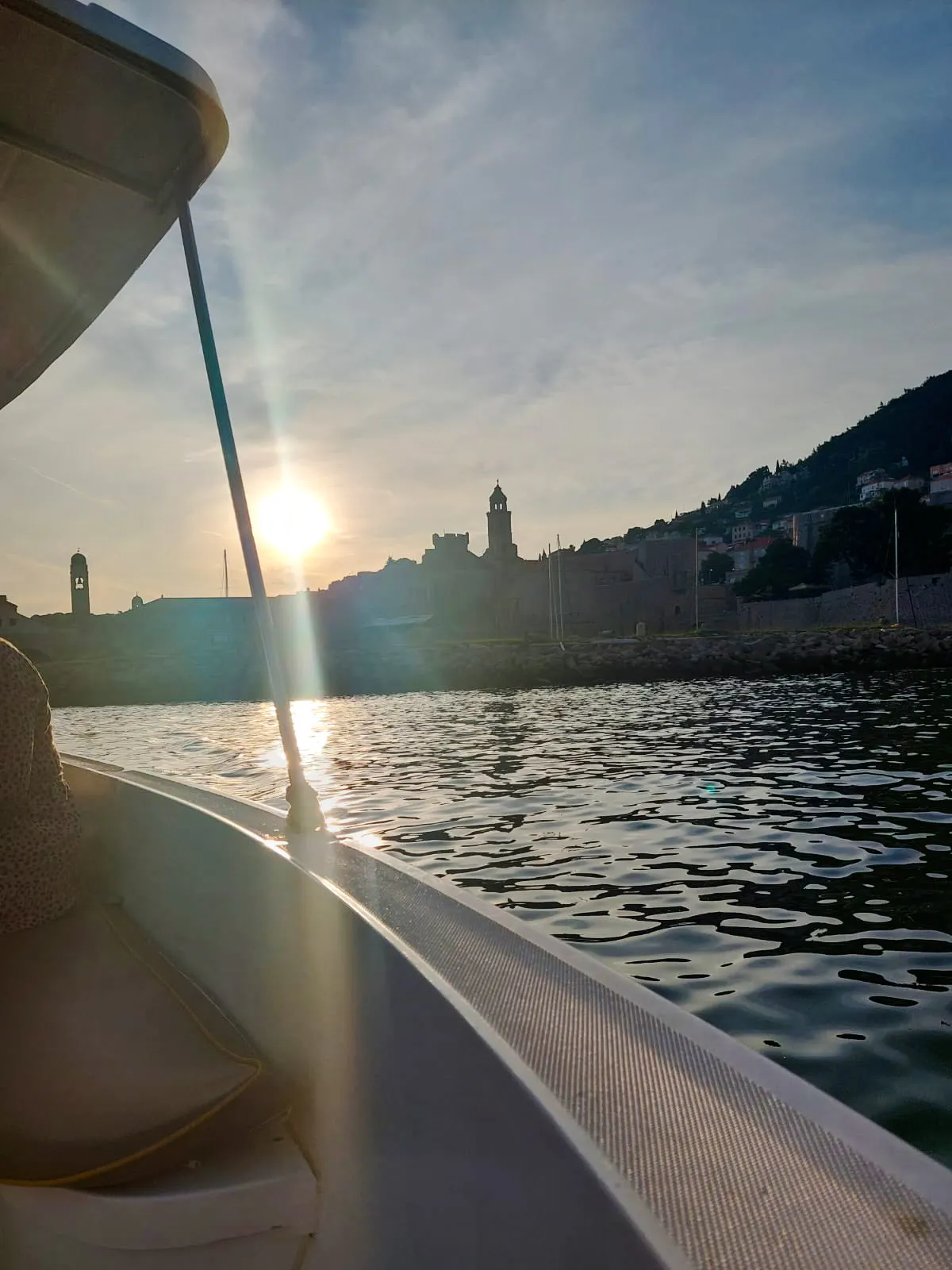 Boat view of Dubrovnik's historic city walls at sunset.