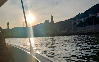 Boat view of Dubrovnik's historic city walls at sunset.