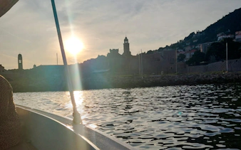 Boat view of Dubrovnik's historic city walls at sunset.