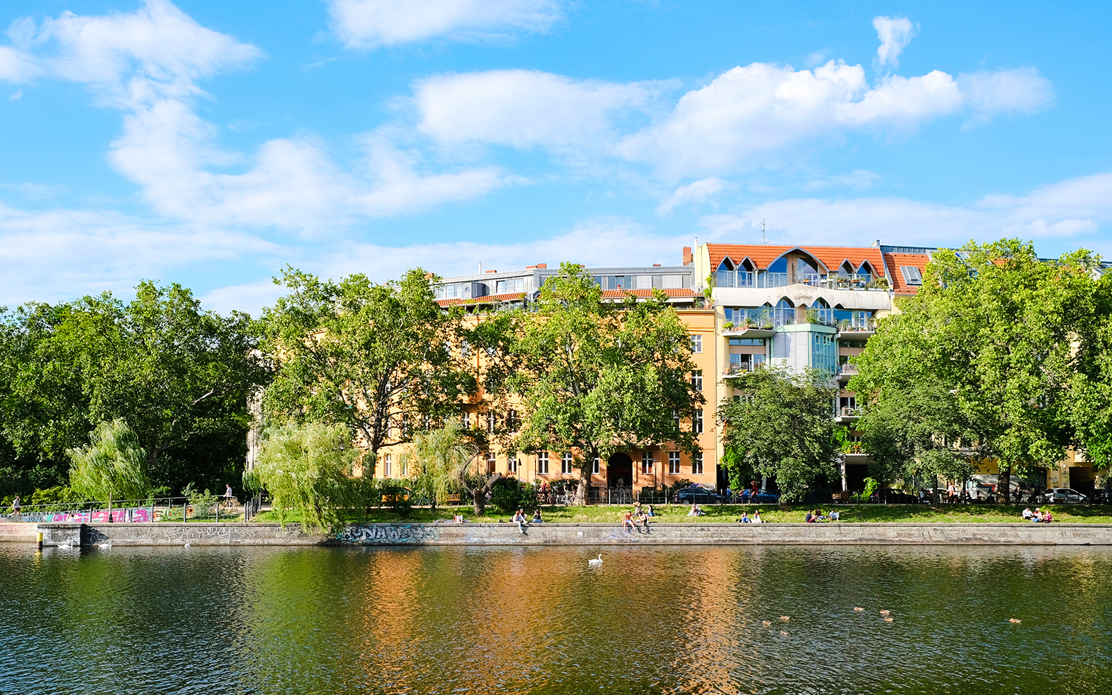 Waterfront view of Urbanhafen, Berlin with trees and buildings along the canal.