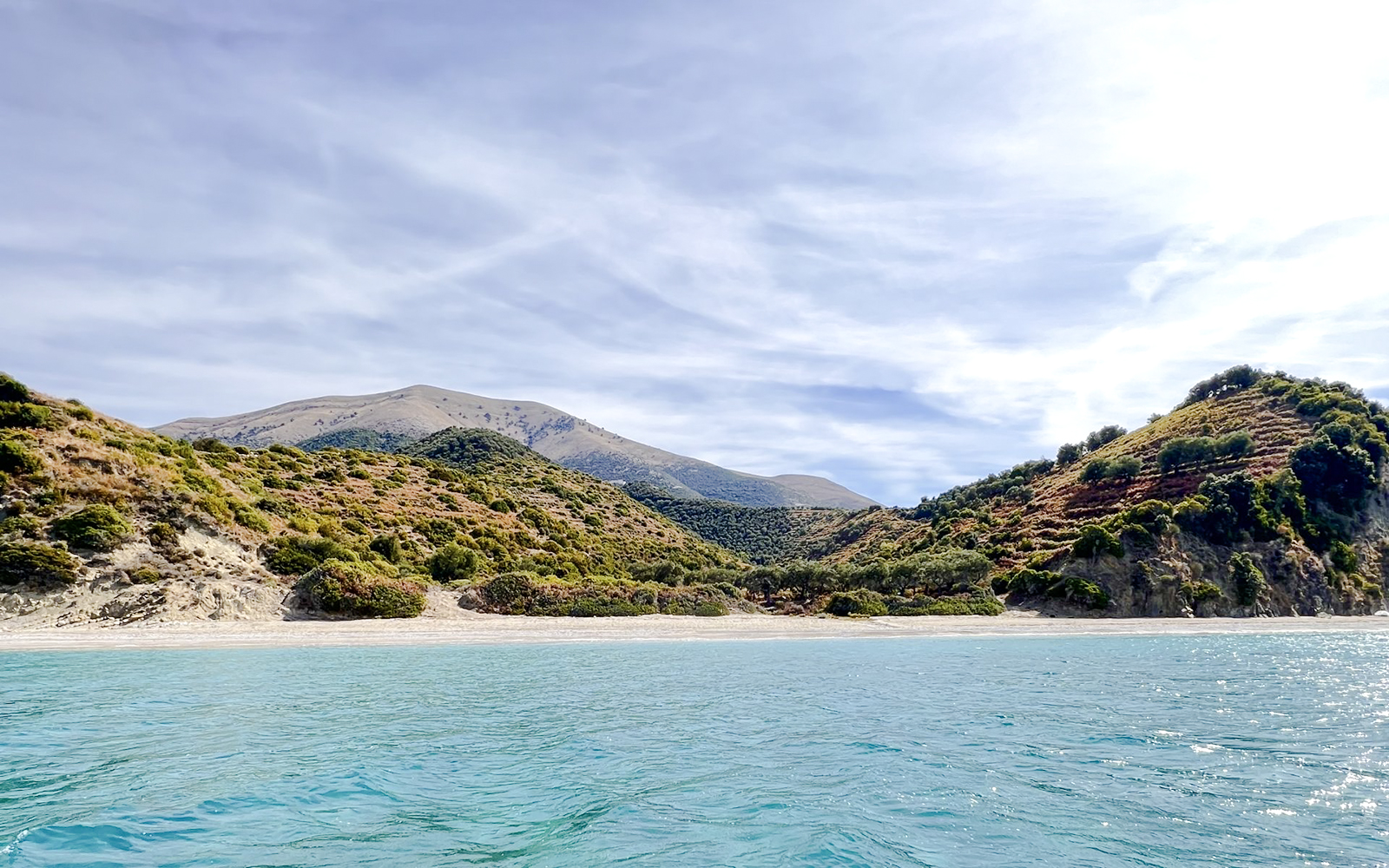 Blue Caves Albania tour featuring coastal landscape with clear water and lush hills.