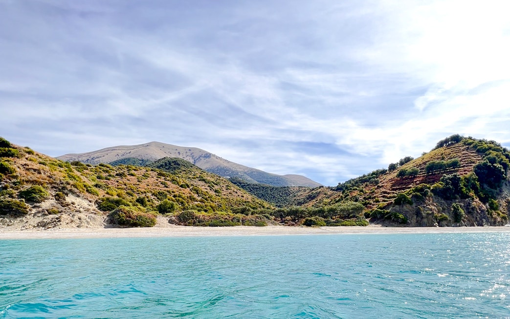 Blue Caves Albania tour featuring coastal landscape with clear water and lush hills.