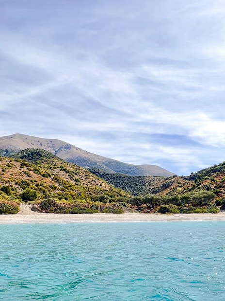 Blue Caves Albania tour featuring coastal landscape with clear water and lush hills.
