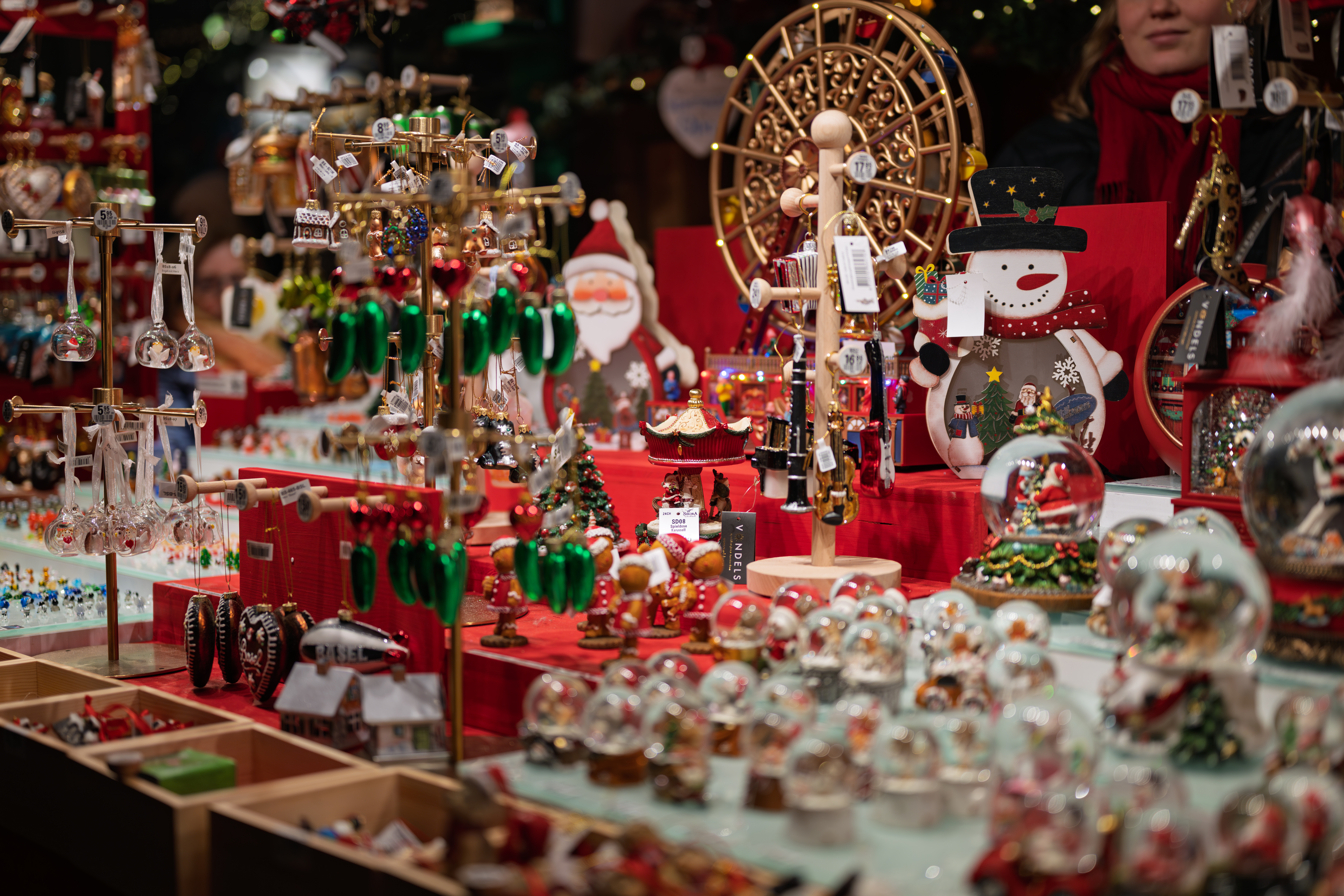 Christmas market stall with festive decorations, including snow globes, ornaments, and Santa figures.