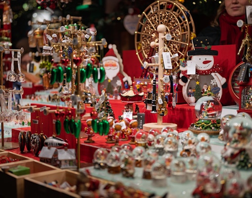 Christmas market stall with festive decorations, including snow globes, ornaments, and Santa figures.