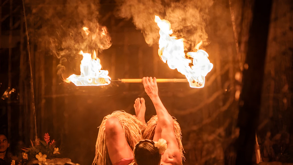 Fire dancer performing with fire poi twirlers at Luau Kalamaku cultural show, Hawaii.