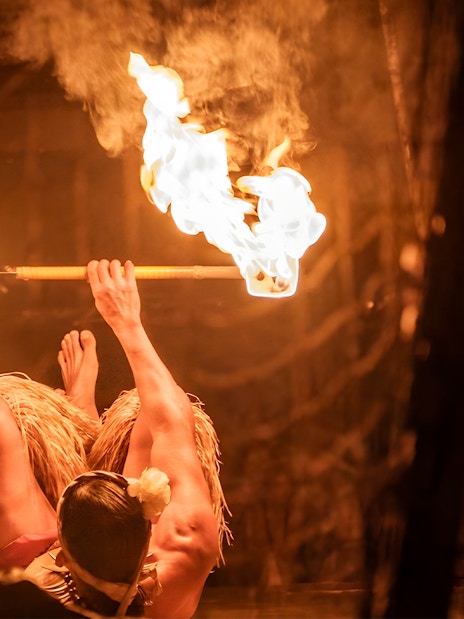 Fire dancer performing with fire poi twirlers at Luau Kalamaku cultural show, Hawaii.