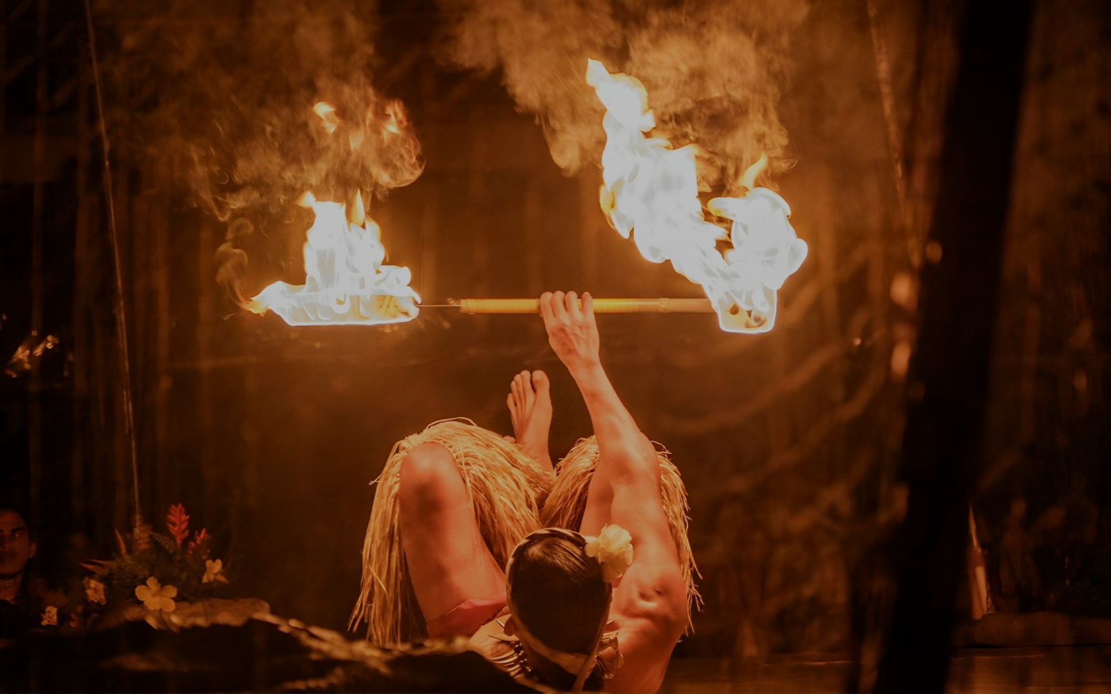 Fire dancer performing with fire poi twirlers at Luau Kalamaku cultural show, Hawaii.