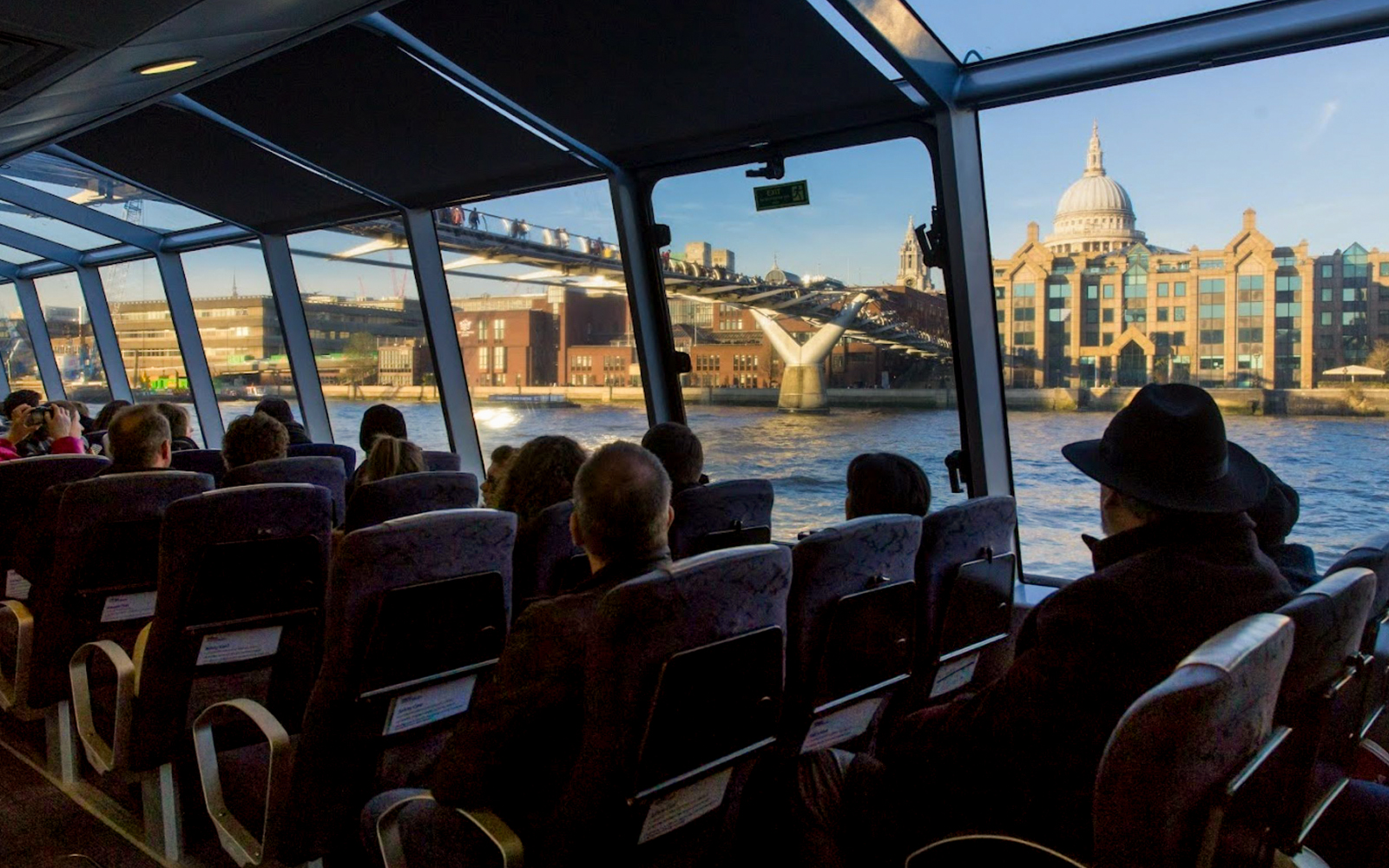 Passengers view Millennium Bridge and St. Paul's Cathedral from an Uber Boat on the Thames in London.
