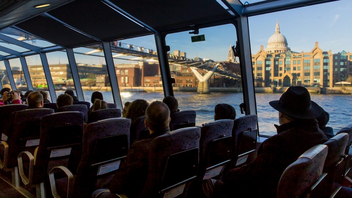 Passengers view Millennium Bridge and St. Paul's Cathedral from an Uber Boat on the Thames in London.
