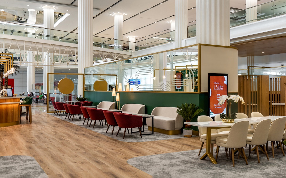 Sitting area in Their Patio Lounge at Dubai International Airport with red chairs and modern decor.