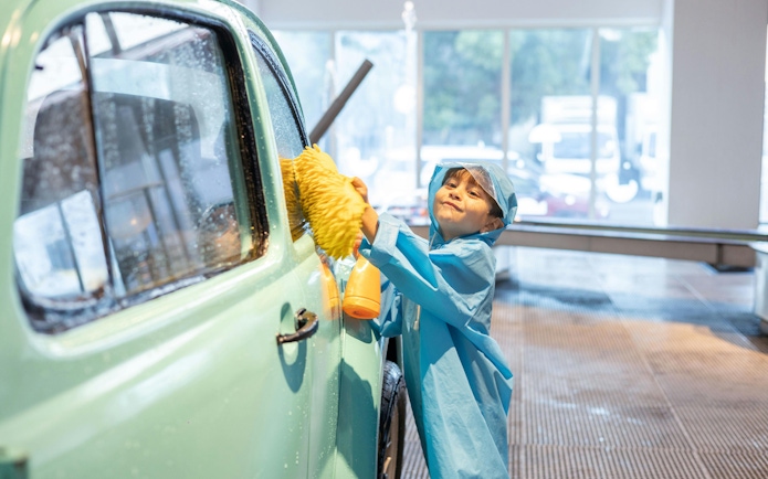 Child cleaning car at OliOli Children's Museum interactive exhibit.