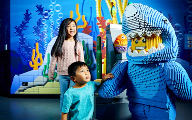 Children interacting with a LEGO shark figure at LEGOLAND Discovery Centre.