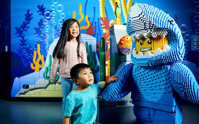 Children interacting with a LEGO shark figure at LEGOLAND Discovery Centre.