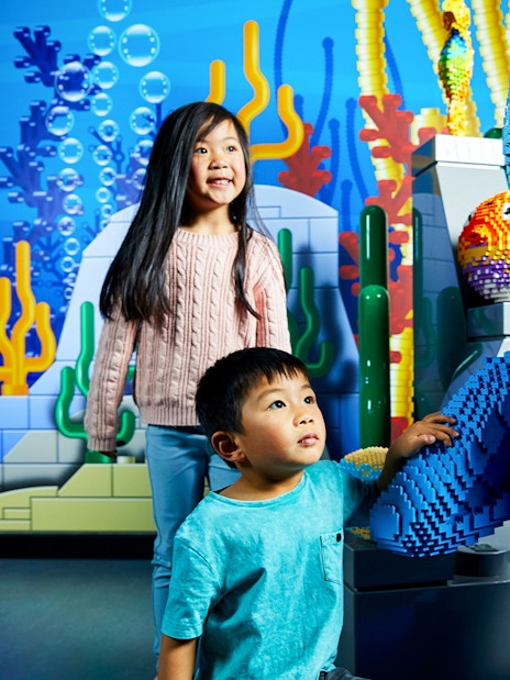Children interacting with a LEGO shark figure at LEGOLAND Discovery Centre.