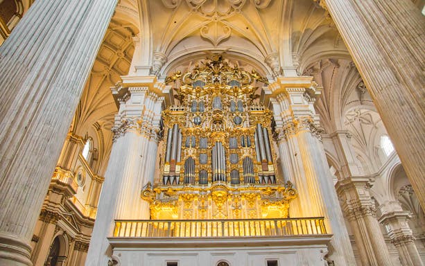 Granada Royal Chapel interior with ornate golden altar and columns.