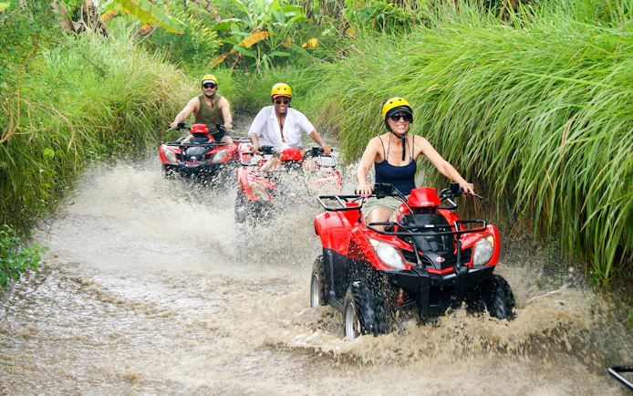 People riding ATVs through a muddy trail in Bali.