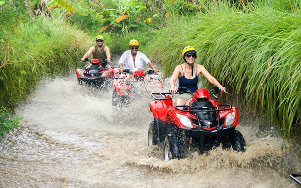 People riding ATVs through a muddy trail in Bali.