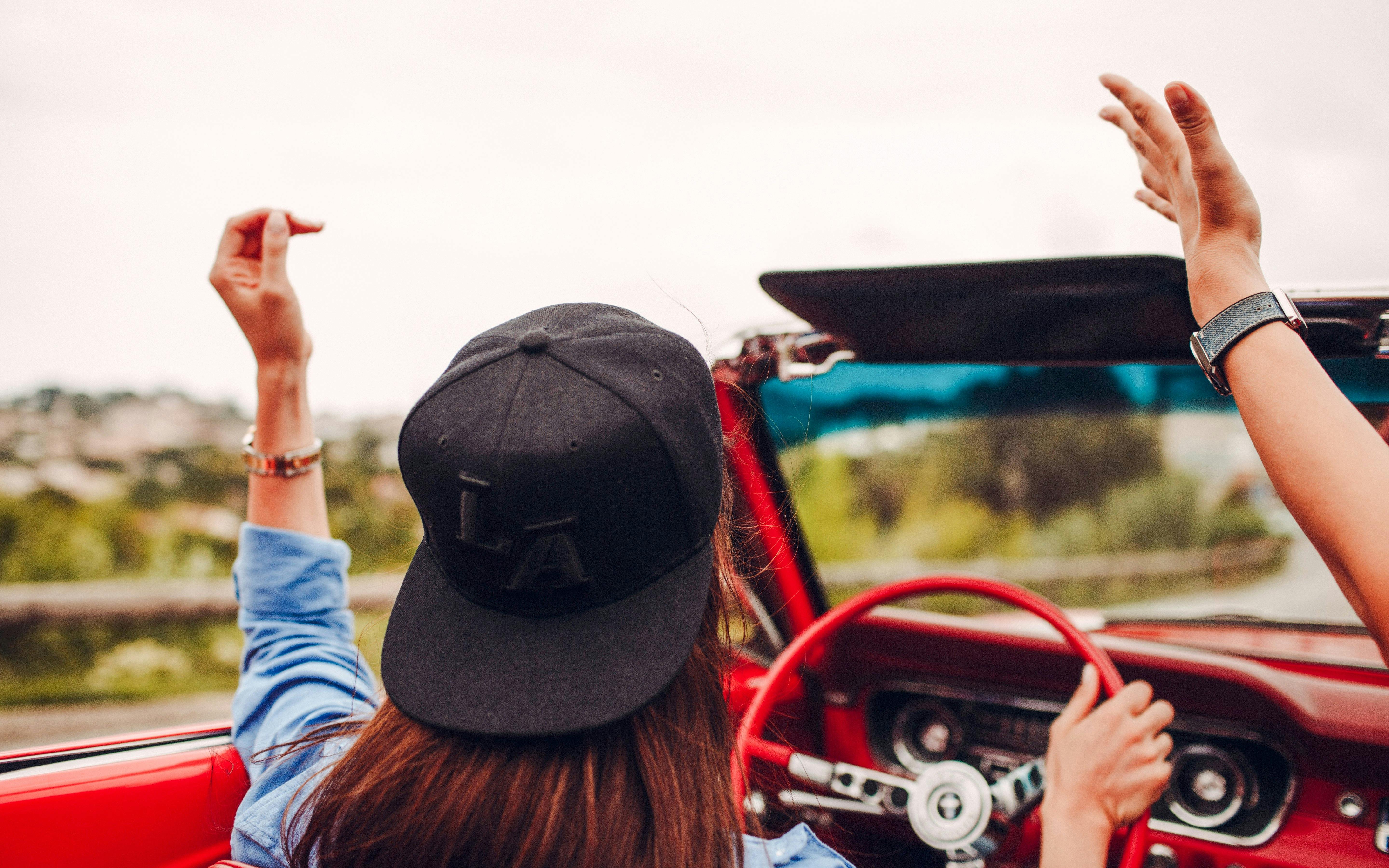 Convertible drive along the French Riviera with hands raised in joy.