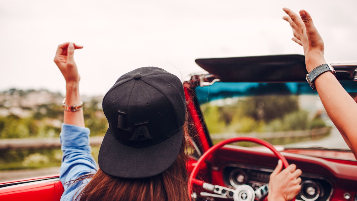 Convertible drive along the French Riviera with hands raised in joy.