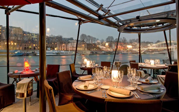 Romantic dinner setup on Bateaux Parisiens cruise with Seine River view, Paris.
