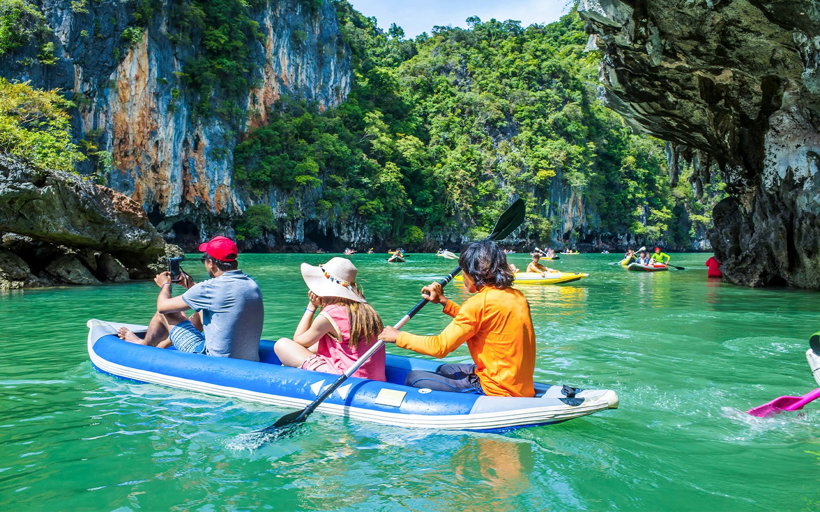 Group kayaking through limestone cliffs in Thailand.