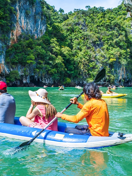 Group kayaking through limestone cliffs in Thailand.