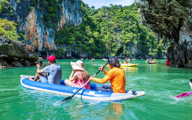 Group kayaking through limestone cliffs in Thailand.