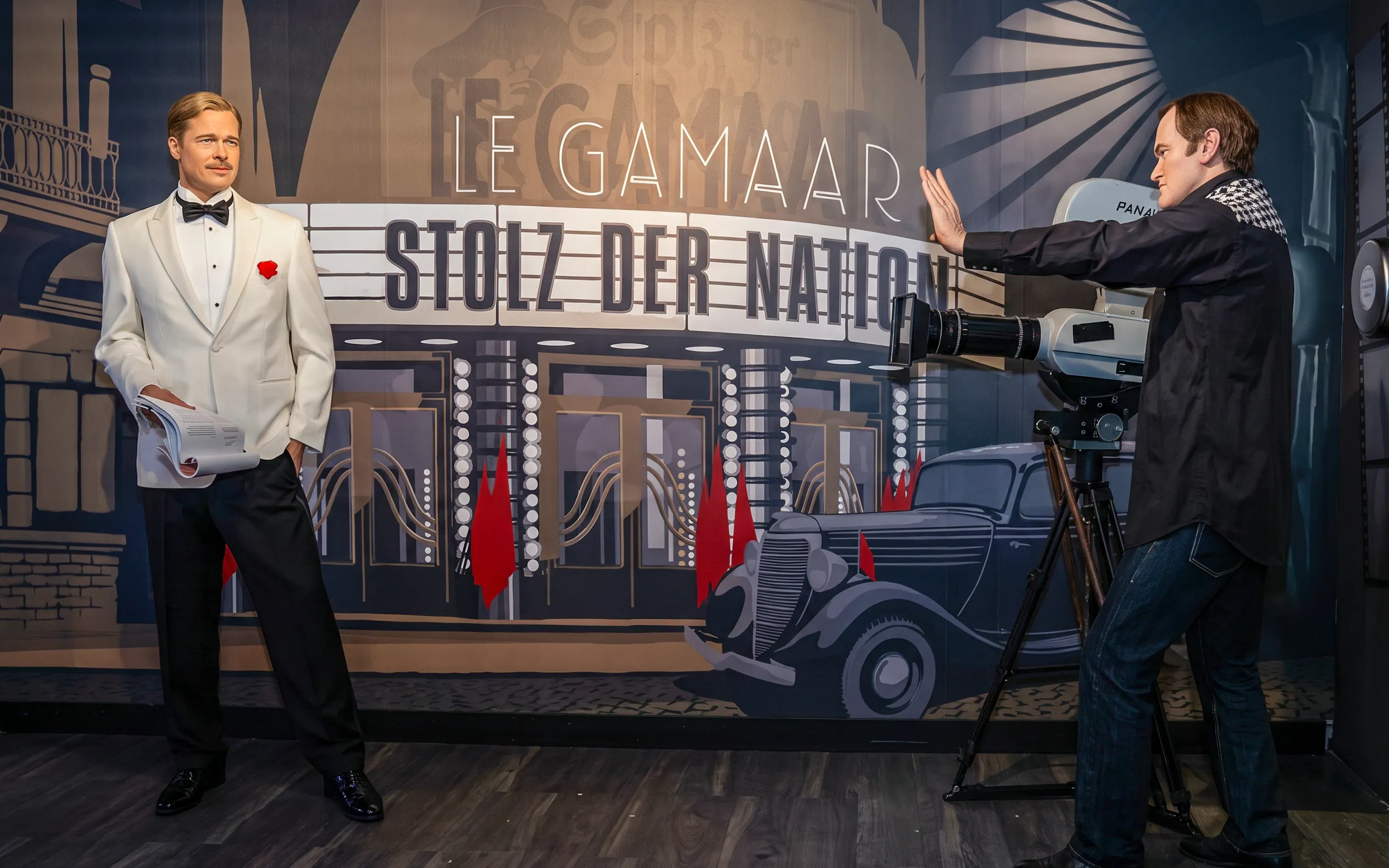 Wax figure of a man in a white tuxedo at Madame Tussauds Vienna, with a vintage film set backdrop.