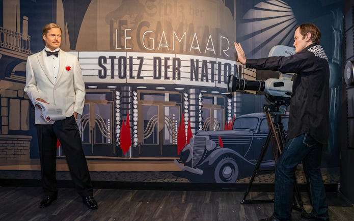 Wax figure of a man in a white tuxedo at Madame Tussauds Vienna, with a vintage film set backdrop.