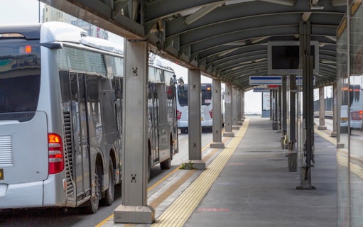 Buses at a covered station platform, part of unlimited public transportation service.