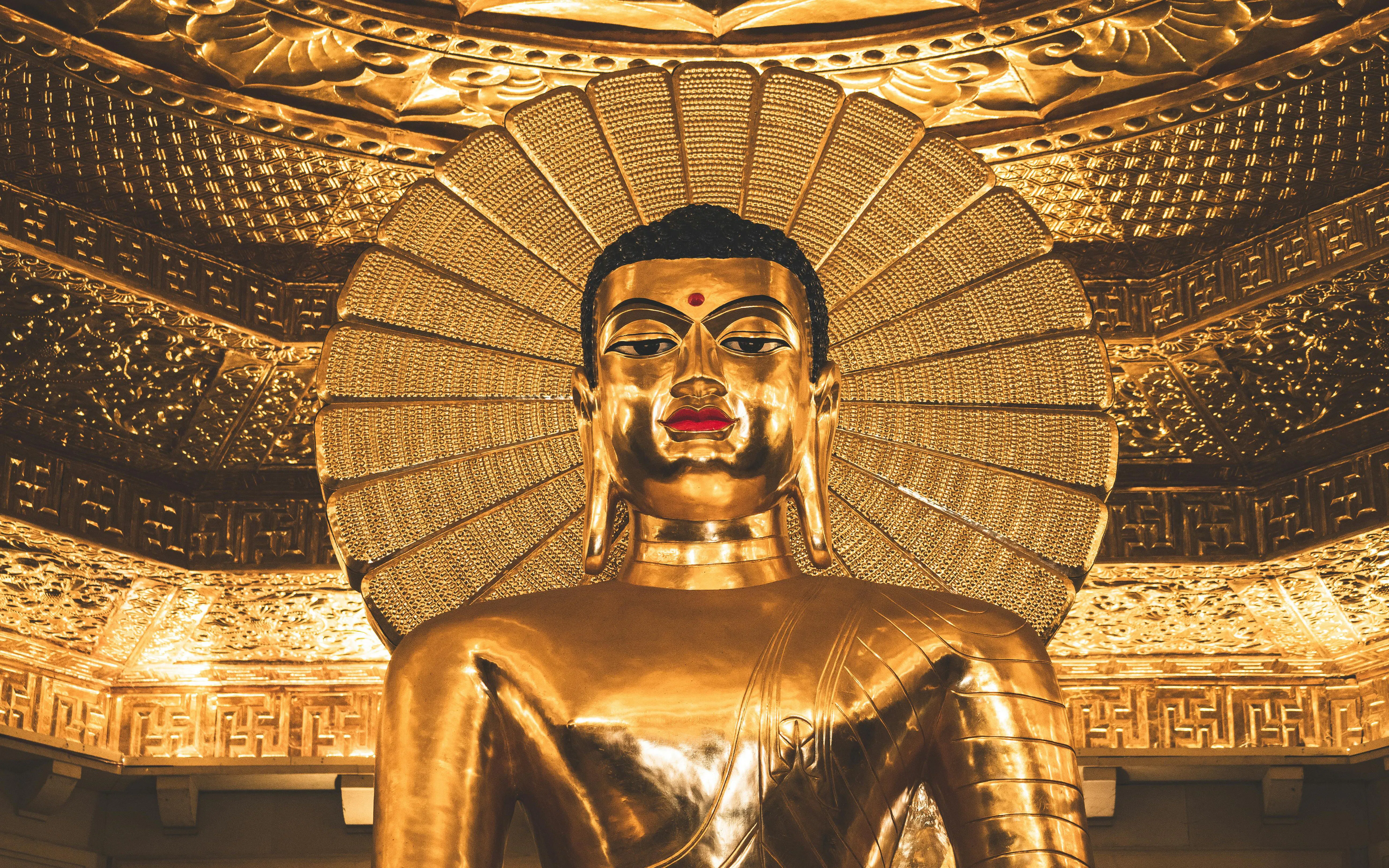 Golden Buddha statue with intricate halo and ornate ceiling details.