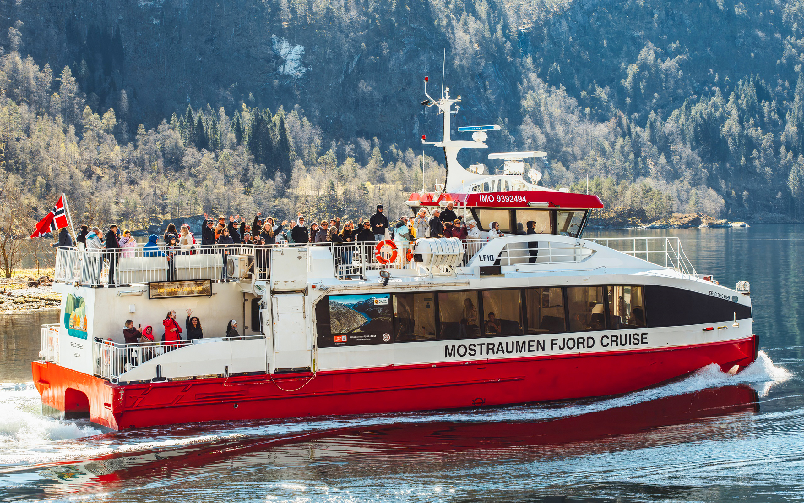 Cruise boat with passengers on Mostraumen Fjord near Bergen, Norway.