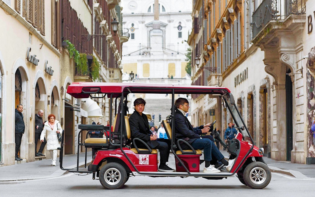 Golf cart tour passing through a street in Rome with the Spanish Steps in the background.
