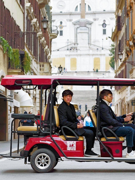 Golf cart tour passing through a street in Rome with the Spanish Steps in the background.