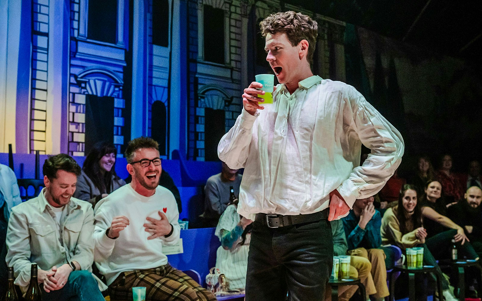 Actor performing in "Plied and Prejudice" with audience laughing in the background.