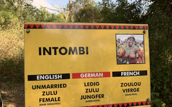 Sign explaining "Intombi" with translations in English, German, and French at Lion Park near Durban.